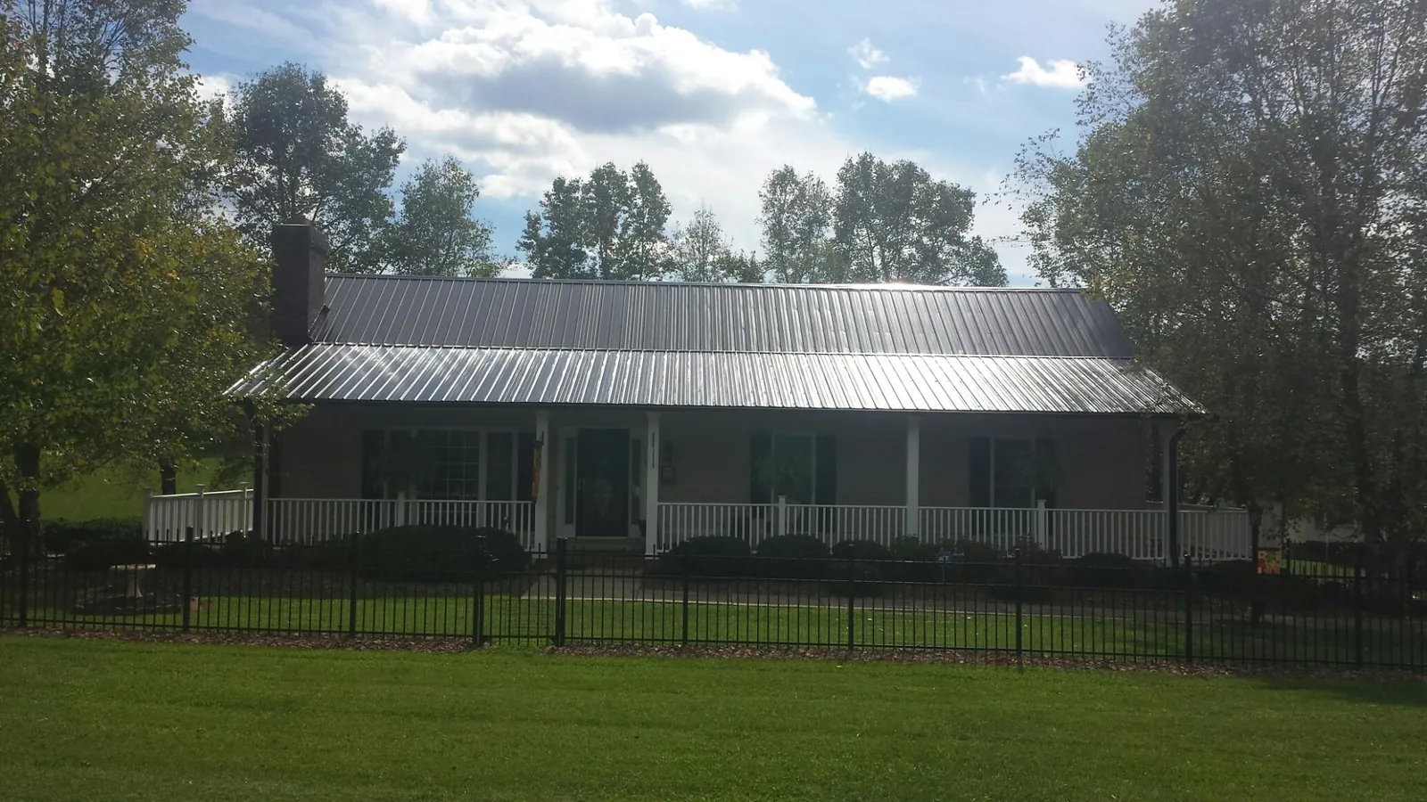 Gray metal roof on a brick ranch with a full width front porch — Gutter Guard Installation work by our crew in Herman