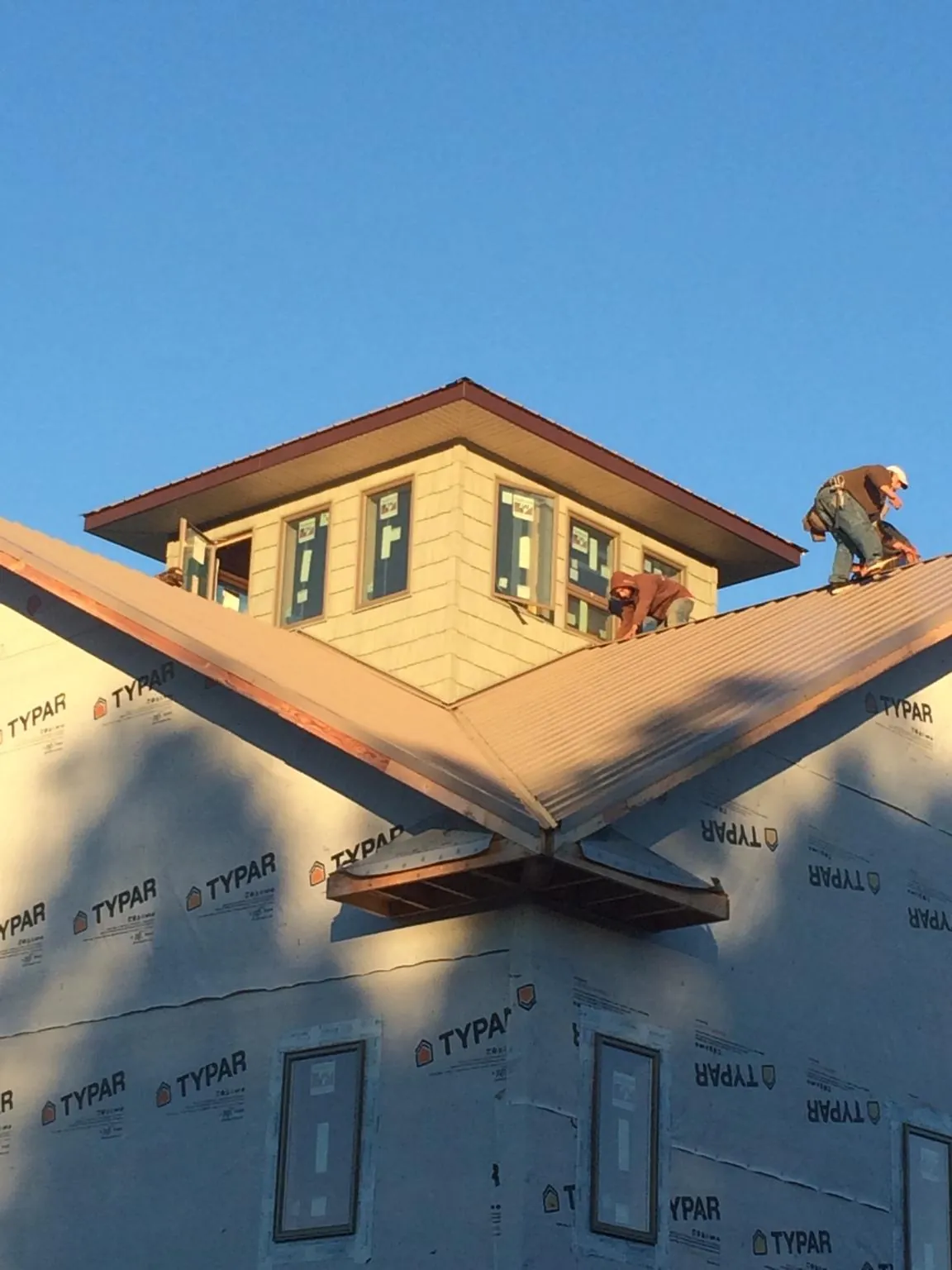 Roofers working around a rooftop cupola on a new metal roof at sunset — Roof Waterproofing in Herman by Roofing Brothers